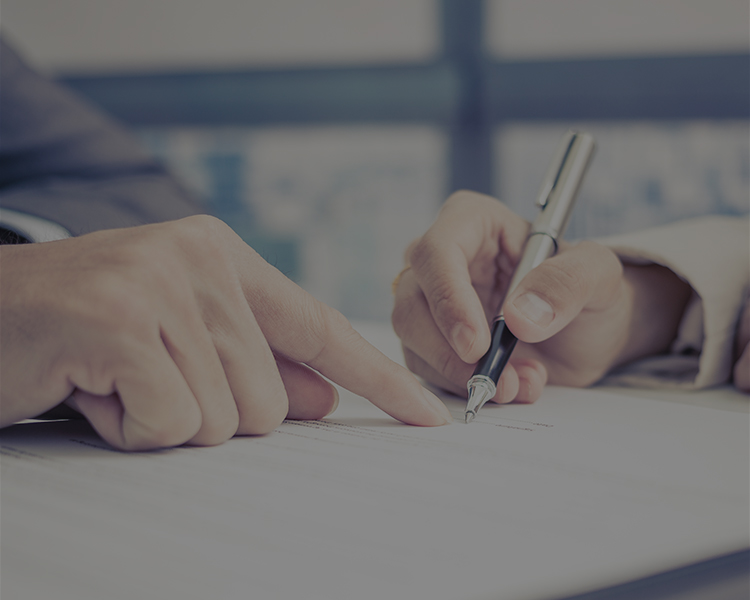 one person pointing at a document and the other holding a pen, focusing on signing or reviewing the document.
